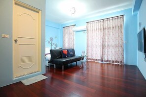 A living room with a sofa, a small table, and a television. - Yi Homestay (Taitung)