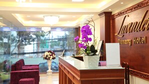 Una recepción con una orquídea en maceta, un candelabro y un letrero que indica Lavender Danang Hotel.