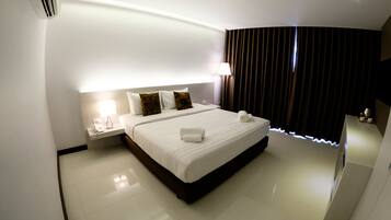 Habitación de hotel moderna con una cama grande, una mesita de noche con lámpara y vistas a la ciudad a través de la ventana.