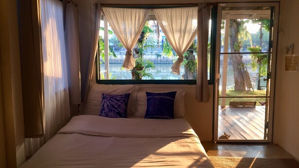 Une chambre à coucher avec un lit, des rideaux et une vue sur une cour.