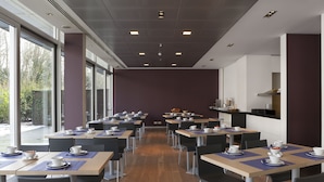 Un vaste espace dédié à la salle à manger, avec de nombreuses tables et chaises, de grandes fenêtres et un aménagement intérieur moderne.