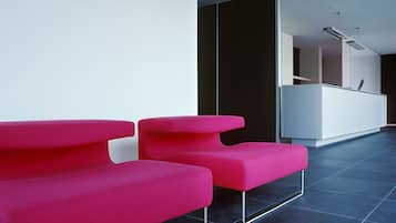 Et moderne receptionsområde med to lyse pink stole og et hvidt skrivebord.