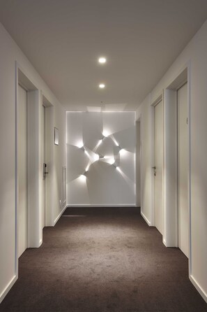 A hallway with a carpeted floor, white walls, and doors on both sides.