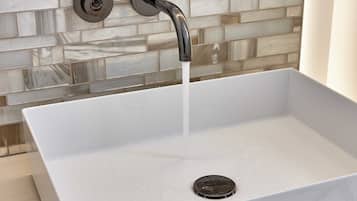 A white rectangular sink with a modern faucet, set against a tiled backsplash.