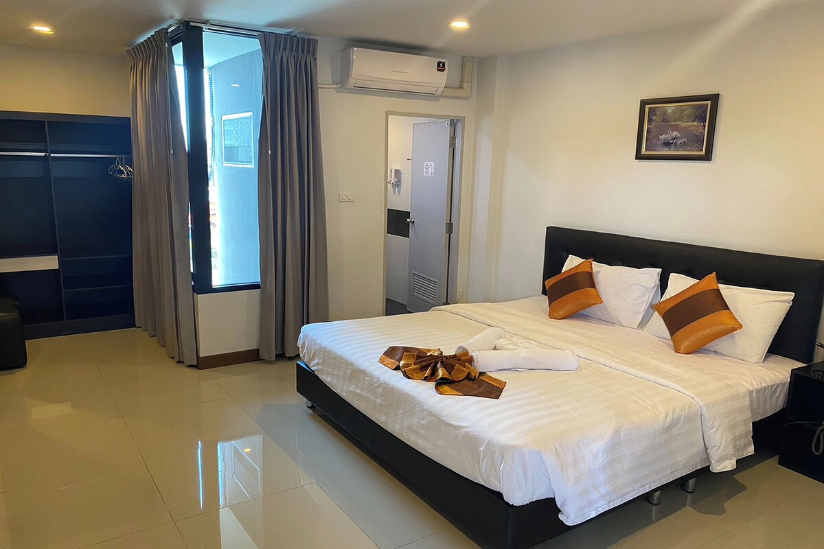 Quarto de hotel com cama, armário, banheiro e janela com cortinas.