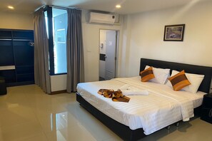 A hotel room with a large bed, a wardrobe, a bathroom, and a view of the outdoors.