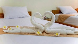 Ein Hotelzimmer mit ordentlich bezogenen Betten, weißen Leinentüchern und einer dekorativen Schwanenform aus Handtüchern auf dem Bett.