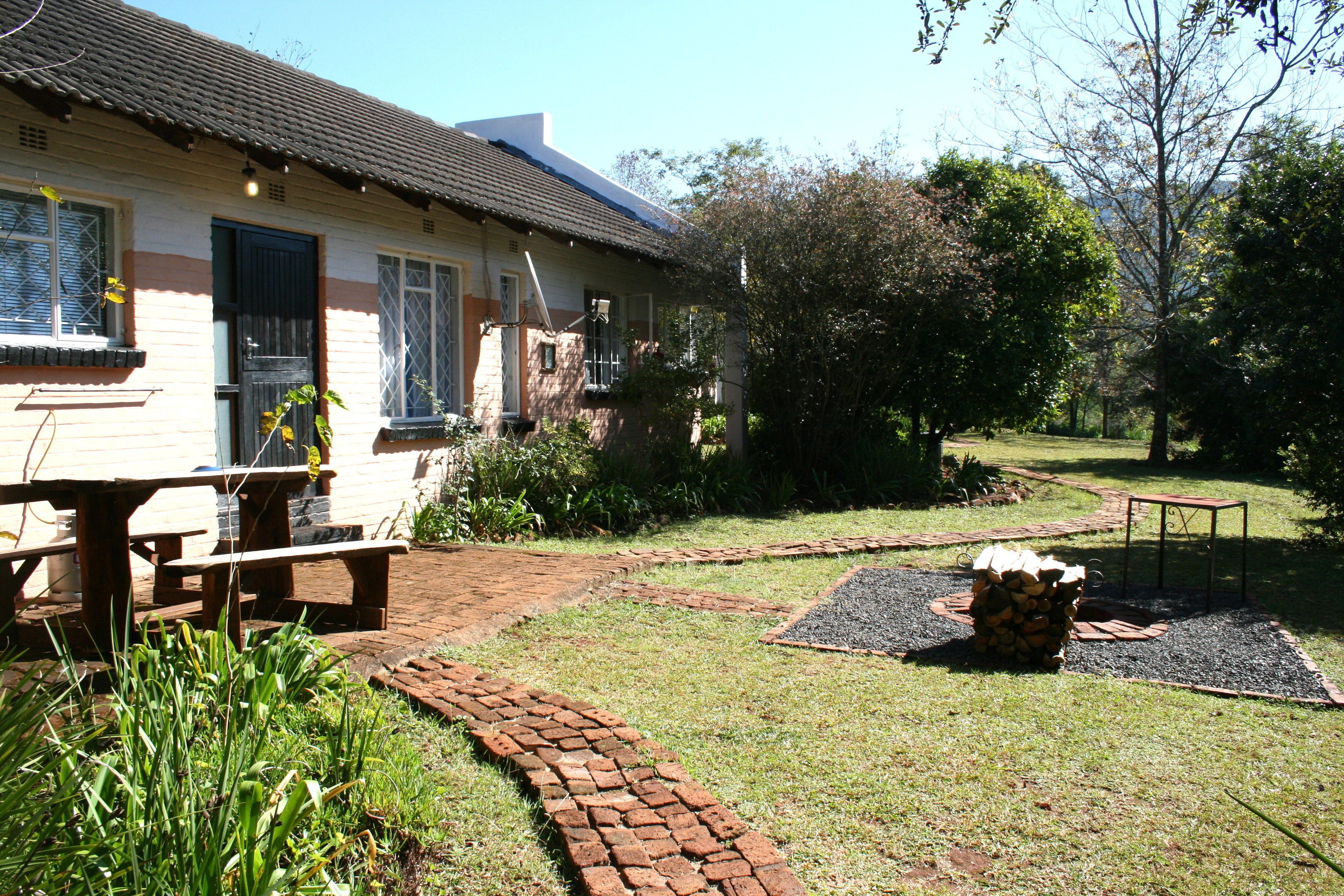 Uma casa com um caminho de tijolos, um banco de madeira e uma pilha de lenha.