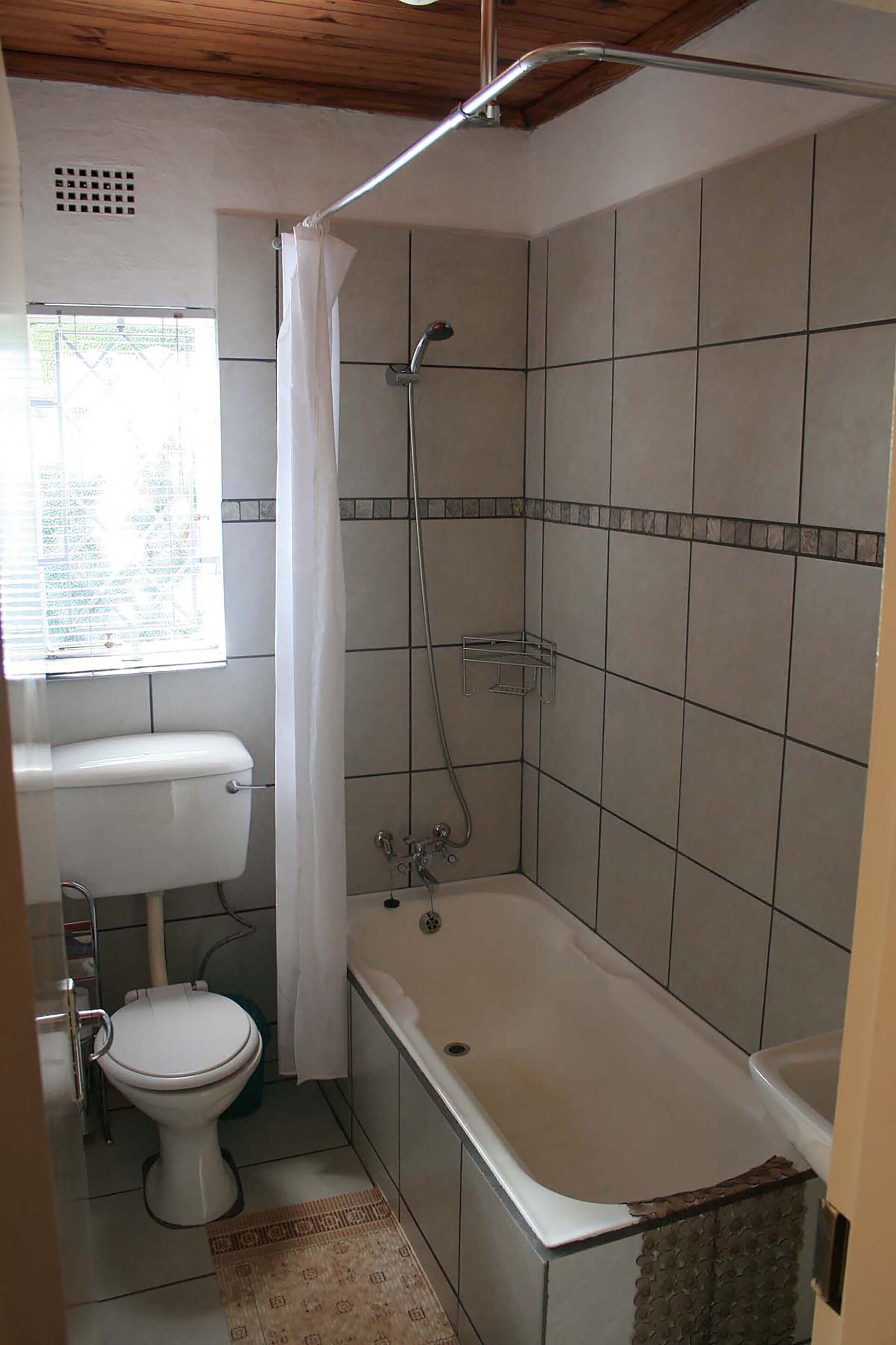 A bathroom with a toilet, bathtub, and shower.