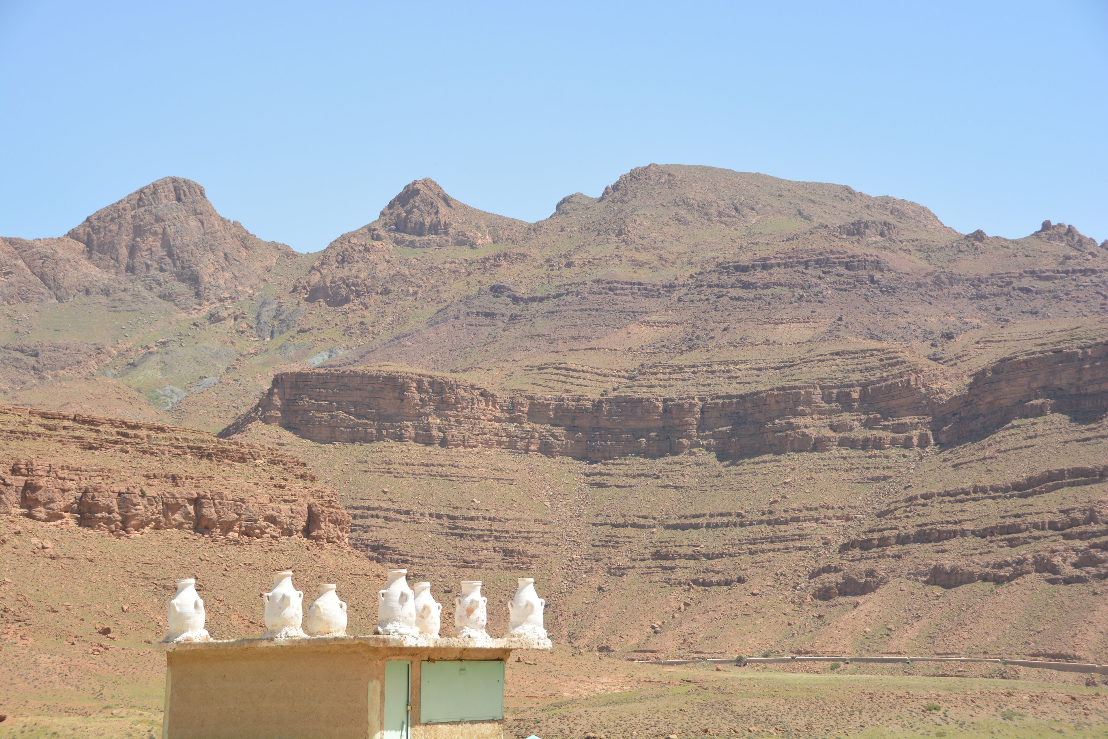 A desert landscape with mountains in the background and a structure with white objects on top.
