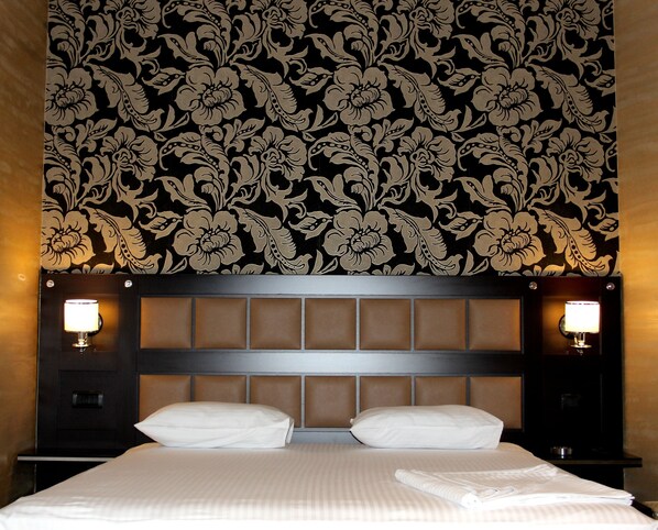 A hotel room with a large bed, two bedside lamps, and a floral wallpaper pattern. - Avan Plaza (Yerevan)