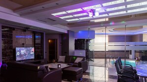 A modern hotel lobby with a large TV, comfortable seating, a glass wall, and a pool area. - Avan Plaza (Yerevan)