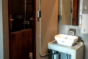 Une salle de bain avec une porte en bois, un lavabo blanc et un miroir au-dessus.