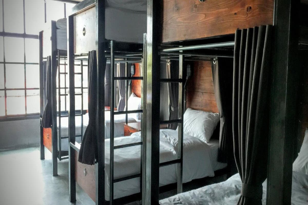 A bunk bed room with metal railings and wooden headboards.
