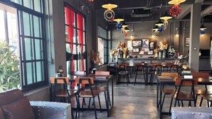 A modern cafe with leather sofas, wooden tables, and hanging decorative lights.