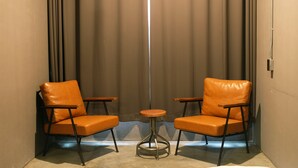 A small room with two orange leather chairs and a small round table.