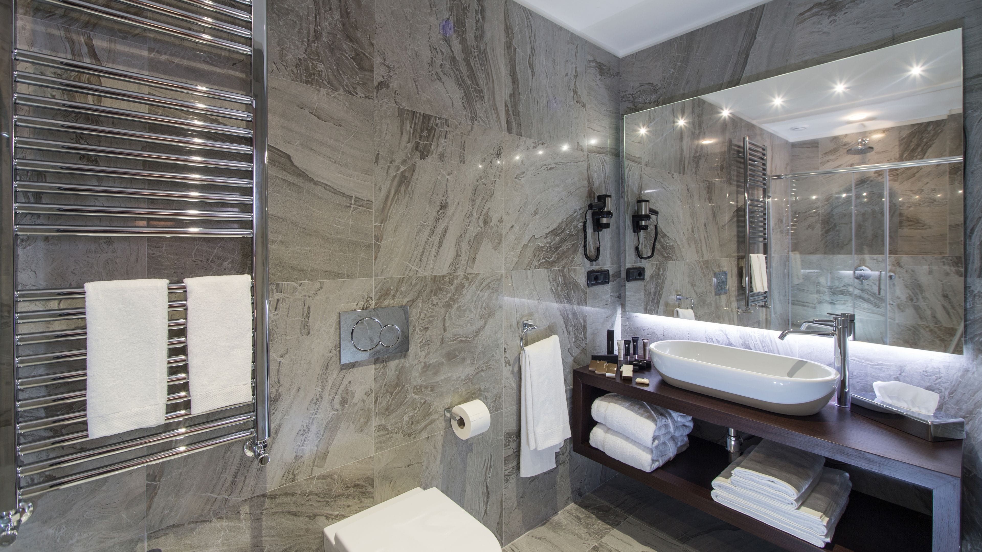 A modern bathroom with a large mirror, a built-in sink, and a glass-enclosed shower.