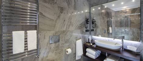 A modern bathroom with a large mirror, a built-in sink, and a glass-enclosed shower.