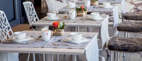 A dining area with tables set for service, chairs, and a decorative wall in the background.