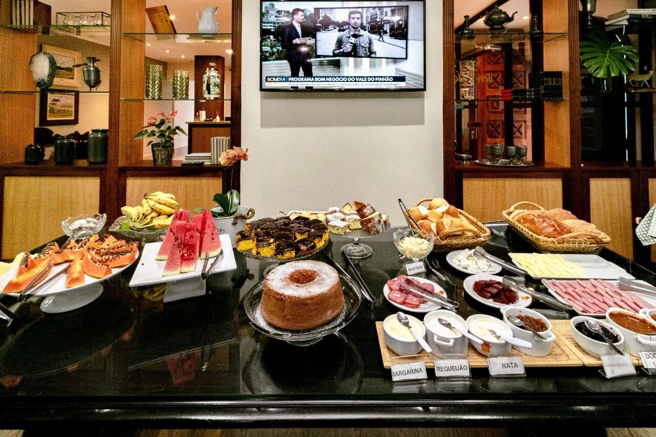 Un bufé con diferentes platillos y una pantalla de televisión mostrando un noticiero.
