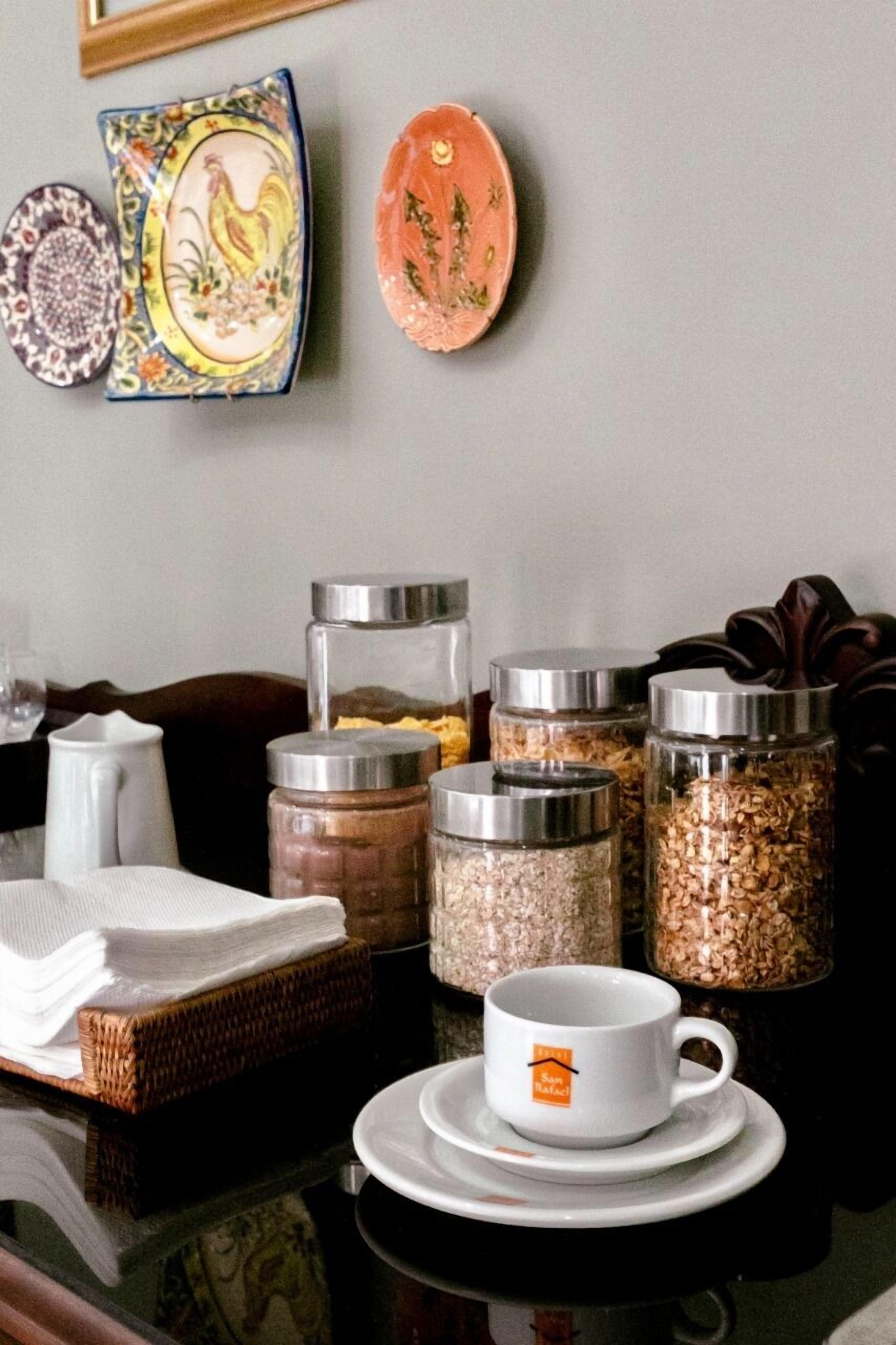 Uma mesa de jantar com uma xícara de café, um jarro e vários potes de grãos.