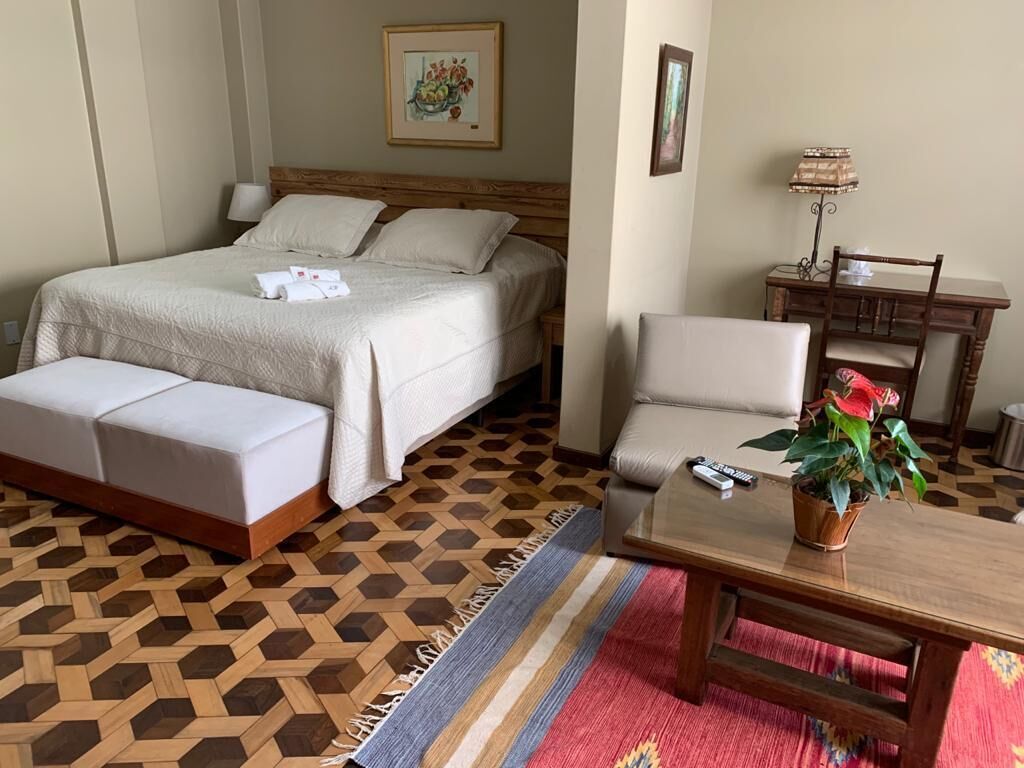 A hotel room with a bed, a sofa, a small table, and a chair.
