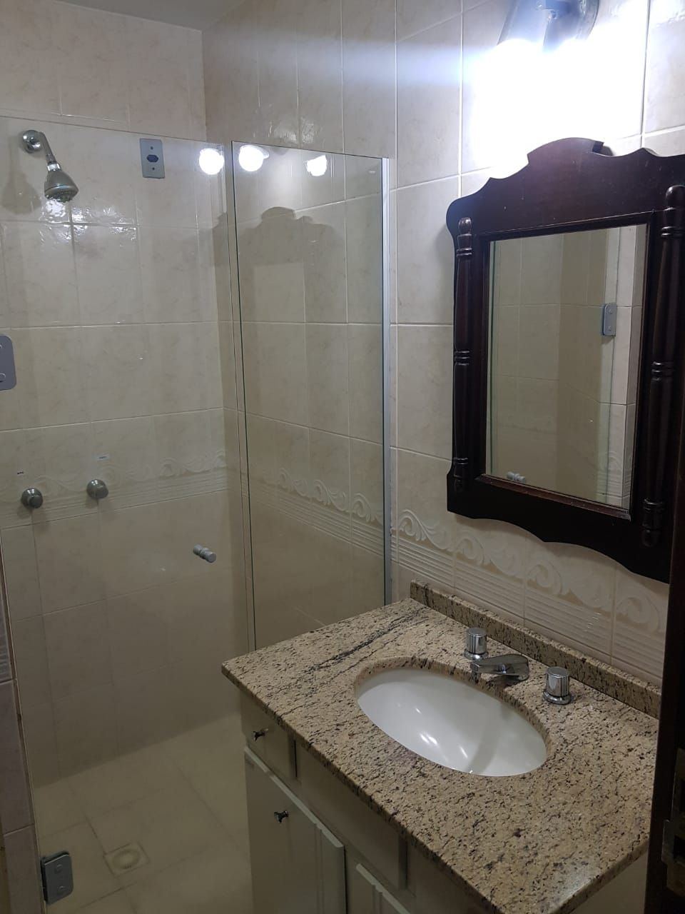 Une salle de bain avec une douche, un lavabo et un miroir.