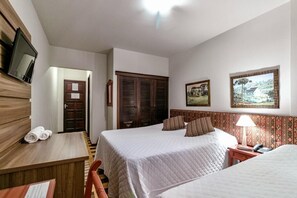 A hotel room with two beds, a desk with a chair, a TV mounted on the wall, and a door leading to another room. - Hotel San Rafael (Porto Uniao)
