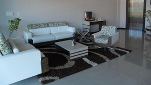 A modern living room with a white sofa, a patterned armchair, a coffee table, and a rug. - Hotel Bell Sttar (Marau)