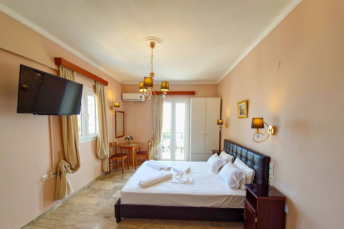 Habitación de hotel con una cama, televisor, escritorio y una silla.