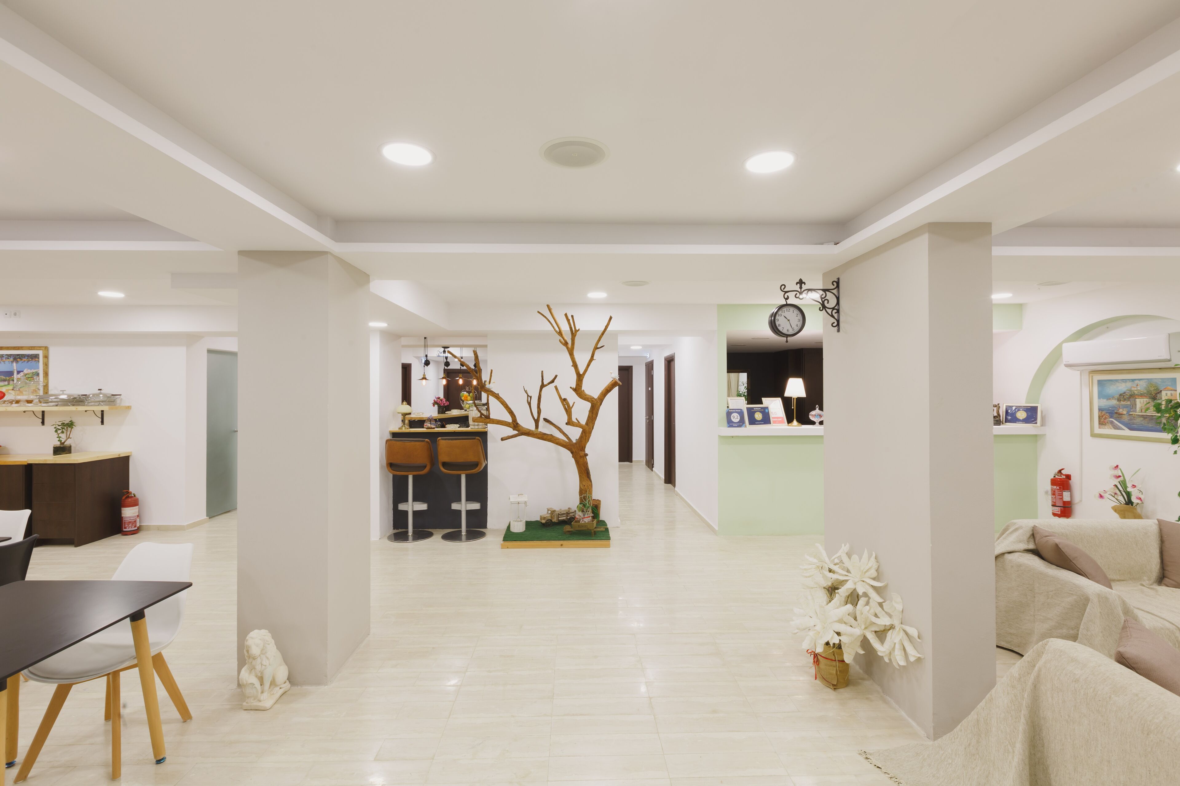 A spacious, modern hotel lobby with a central seating area, a reception desk, and a dining area.