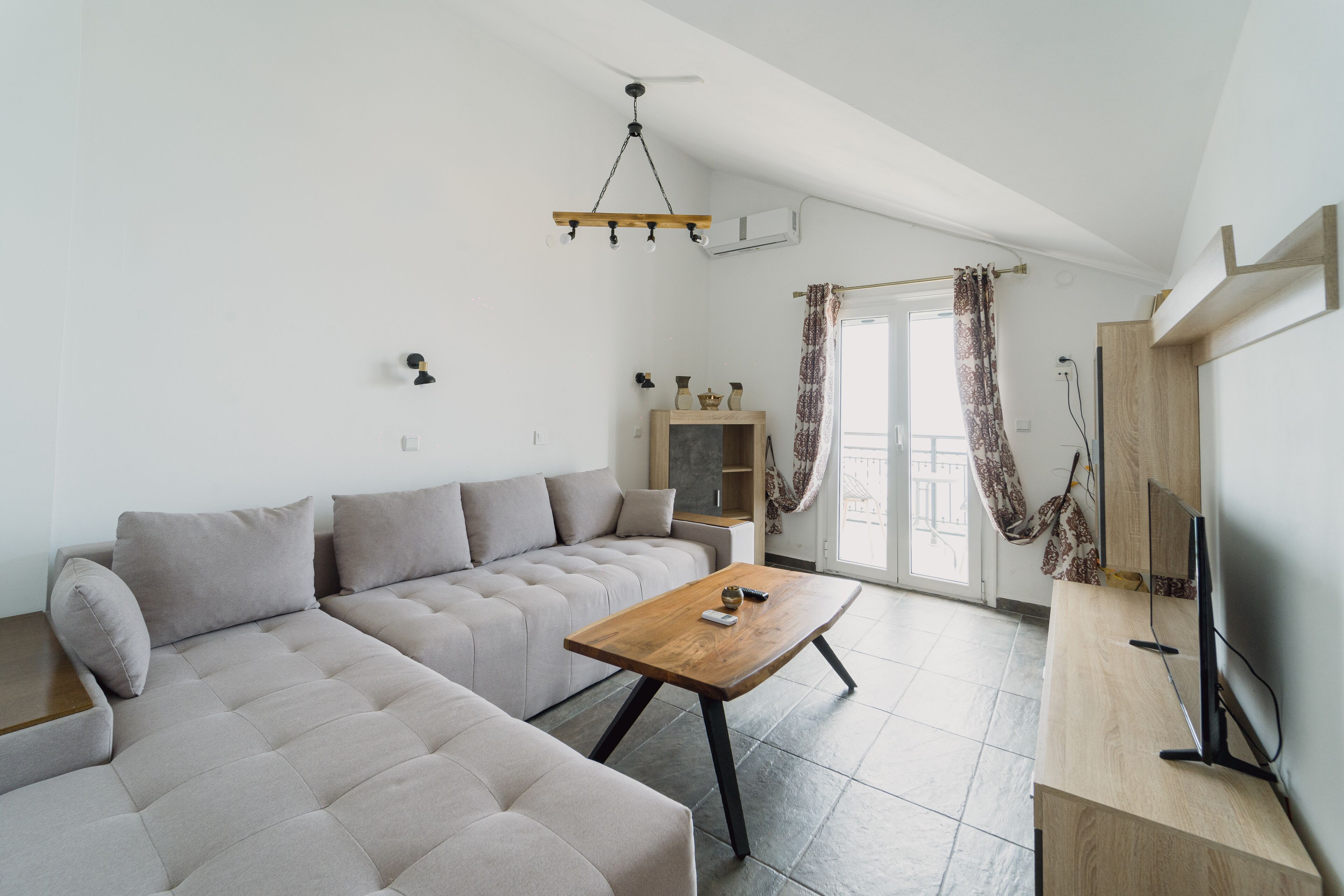 A modern living room with a sectional sofa, a wooden coffee table, and a flat-screen TV.