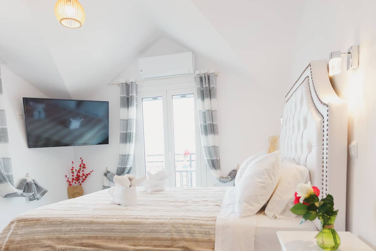 Un dormitorio moderno con una cama grande, un televisor de pantalla plana en la pared y una mesita de noche con un florero.