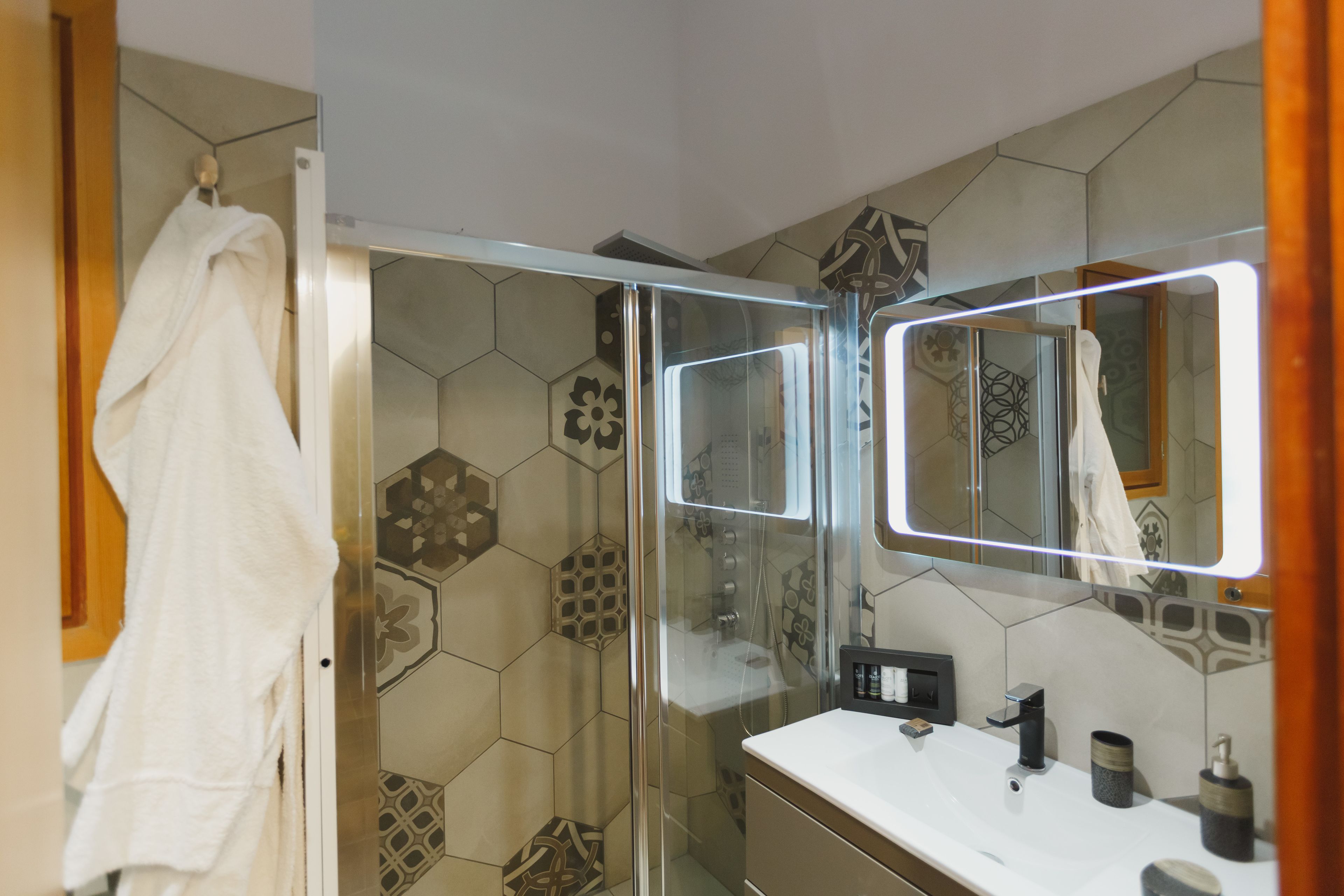 Un baño moderno con cabina de ducha de vidrio, un lavabo blanco y un espejo grande.