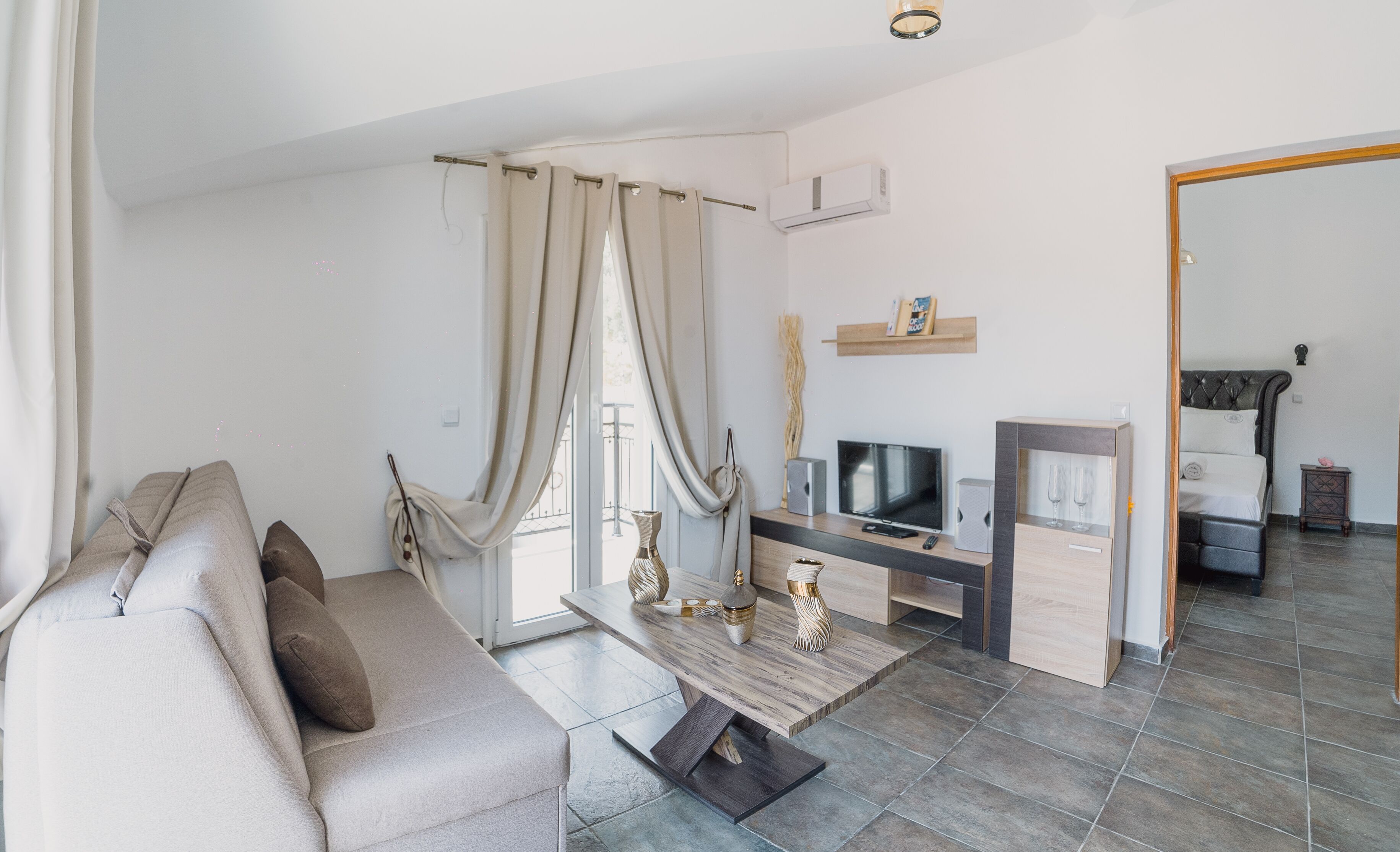A modern living room with a sofa, TV, and a small table with decorative items.