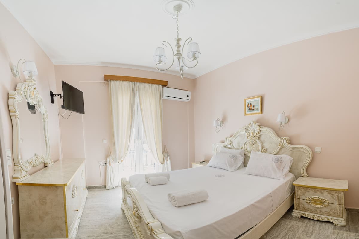 Un dormitorio con una cama grande, un tocador con espejo, una televisión y una araña.