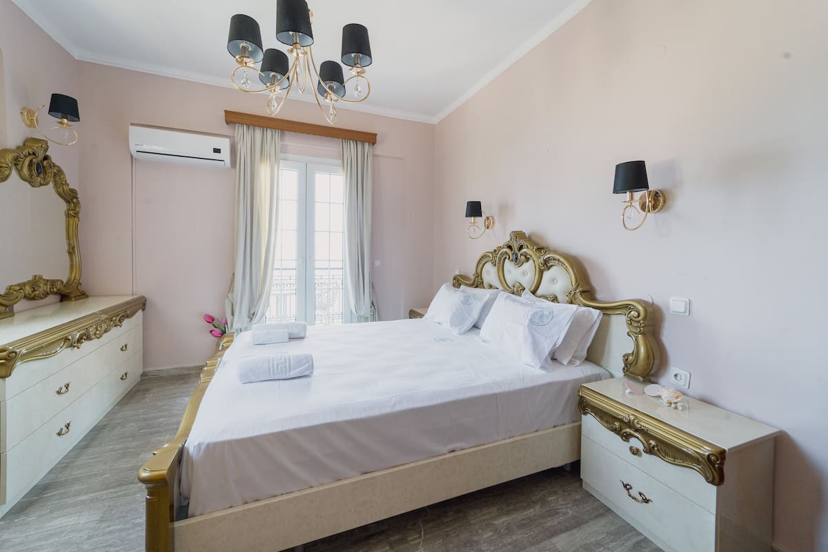 Un dormitorio con una cama grande, mesitas de noche, un aparador, aire acondicionado y un candelabro.