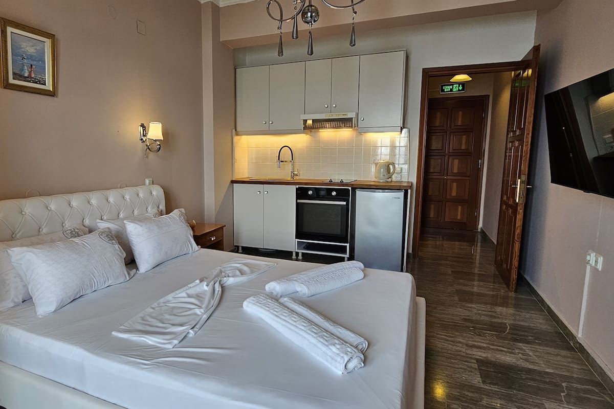 Habitación de hotel con una cama grande, kitchenette, televisor montado en la pared y un cuadro.