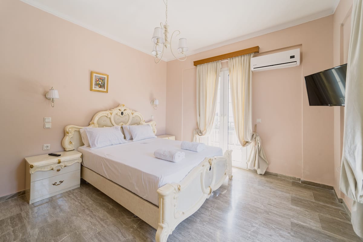 Un dormitorio con una cama grande, mesitas de noche, un candelabro, un aire acondicionado y un televisor.