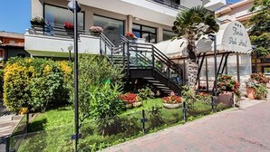 A modern hotel with a staircase leading to a balcony, surrounded by well-maintained gardens and a sign indicating a park hotel. - Hotel Florida Park (Bellaria-Igea Marina)