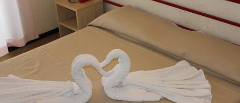 Una cama bien hecha con dos toallas formando la figura de un cisne.