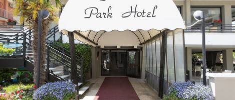 The entrance to the Florida Park Hotel with a red carpet, a palm tree, and potted flowers.