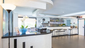 A modern kitchen with a bar area, featuring a curved countertop, bar stools, and a variety of kitchen appliances. - Hotel Florida Park (Bellaria-Igea Marina)