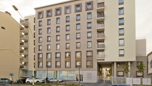 Een hotel met meerdere verdiepingen, met een modern design, een centrale ingang en balkons op elke verdieping.