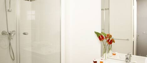 A modern bathroom with a glass-enclosed shower, a white sink, dark wooden cabinets, and a mirror with a tile backsplash.