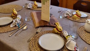 A dining table set with plates, cutlery, and decorative items including a vase with yellow flowers. - Fisherman's Daughter Bed & Breakfast (Mahone Bay)