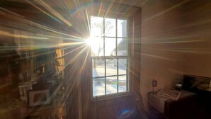 A room with a large window, wooden walls, and a visible door. - Fisherman's Daughter Bed & Breakfast (Mahone Bay)