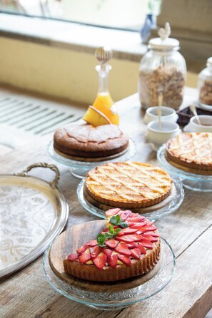 A table with various desserts on glass stands, including cakes and a tart with strawberries. - Fattoria di Maiano (Fiesole)