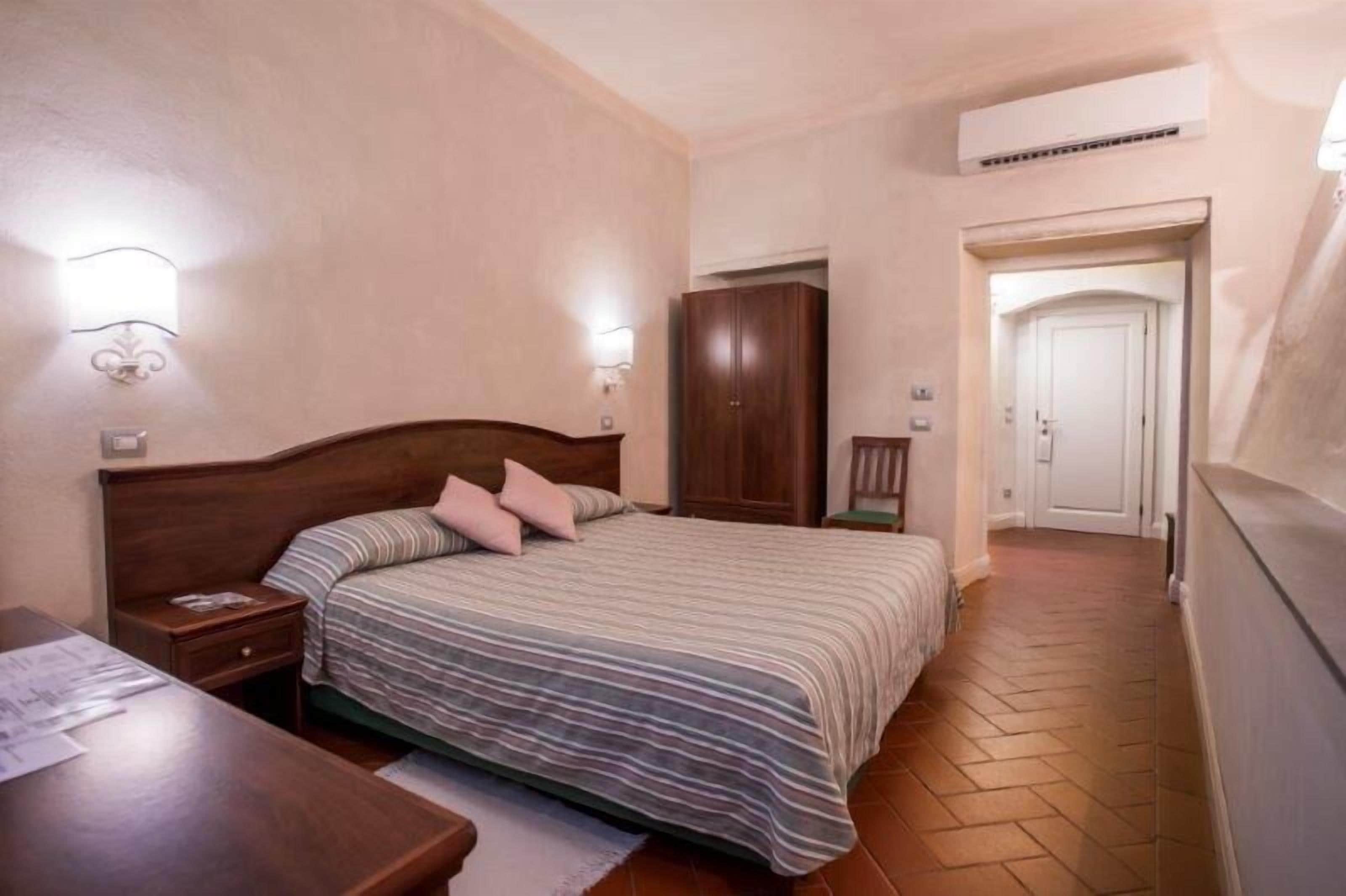 Un dormitorio con cama de madera, una mesita de noche, un armario y un escritorio con papeles.
