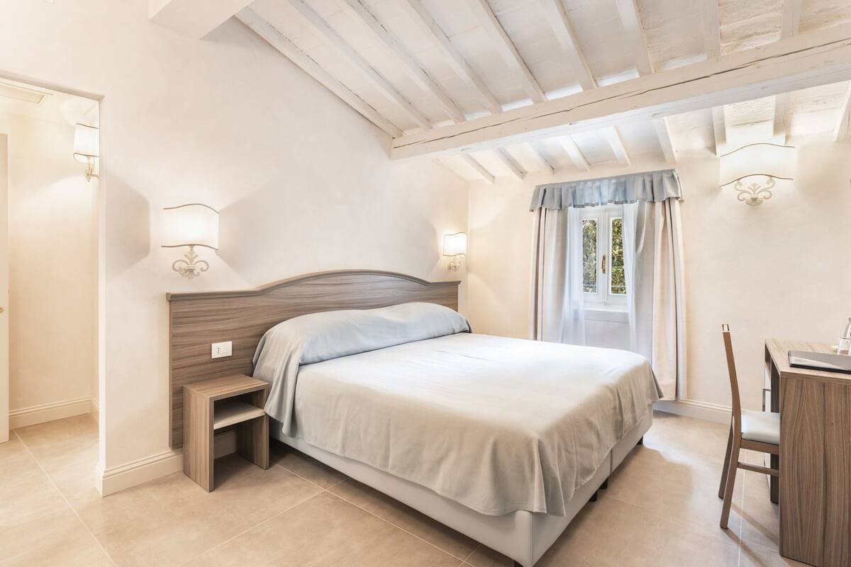 A bedroom with a bed, bedside tables, a desk, and a chair.